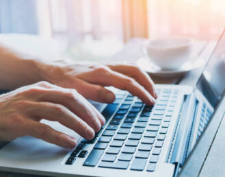 La imagen muestra un primer plano de las manos de una persona de negocios, con la persona trabajando en una computadora. Está utilizando activamente internet y participando en plataformas de redes sociales.