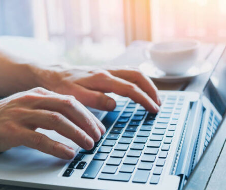 La imagen muestra un primer plano de las manos de una persona de negocios, con la persona trabajando en una computadora. Está utilizando activamente internet y participando en plataformas de redes sociales.